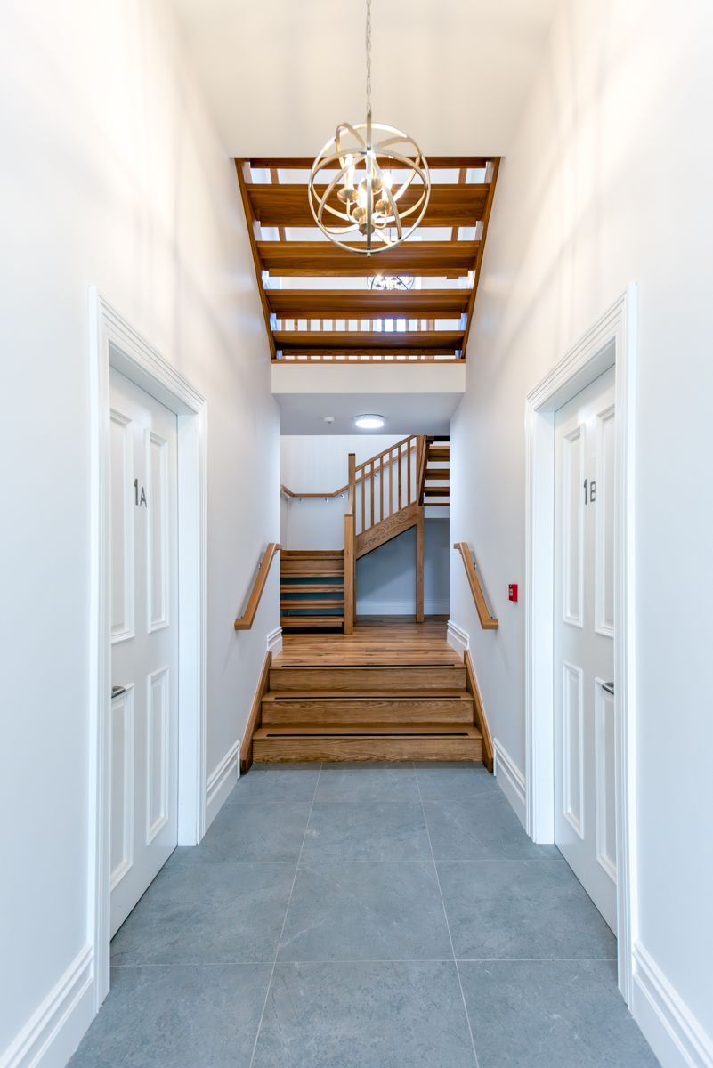 A hallway with stairs and a chandelier hanging from the ceiling.