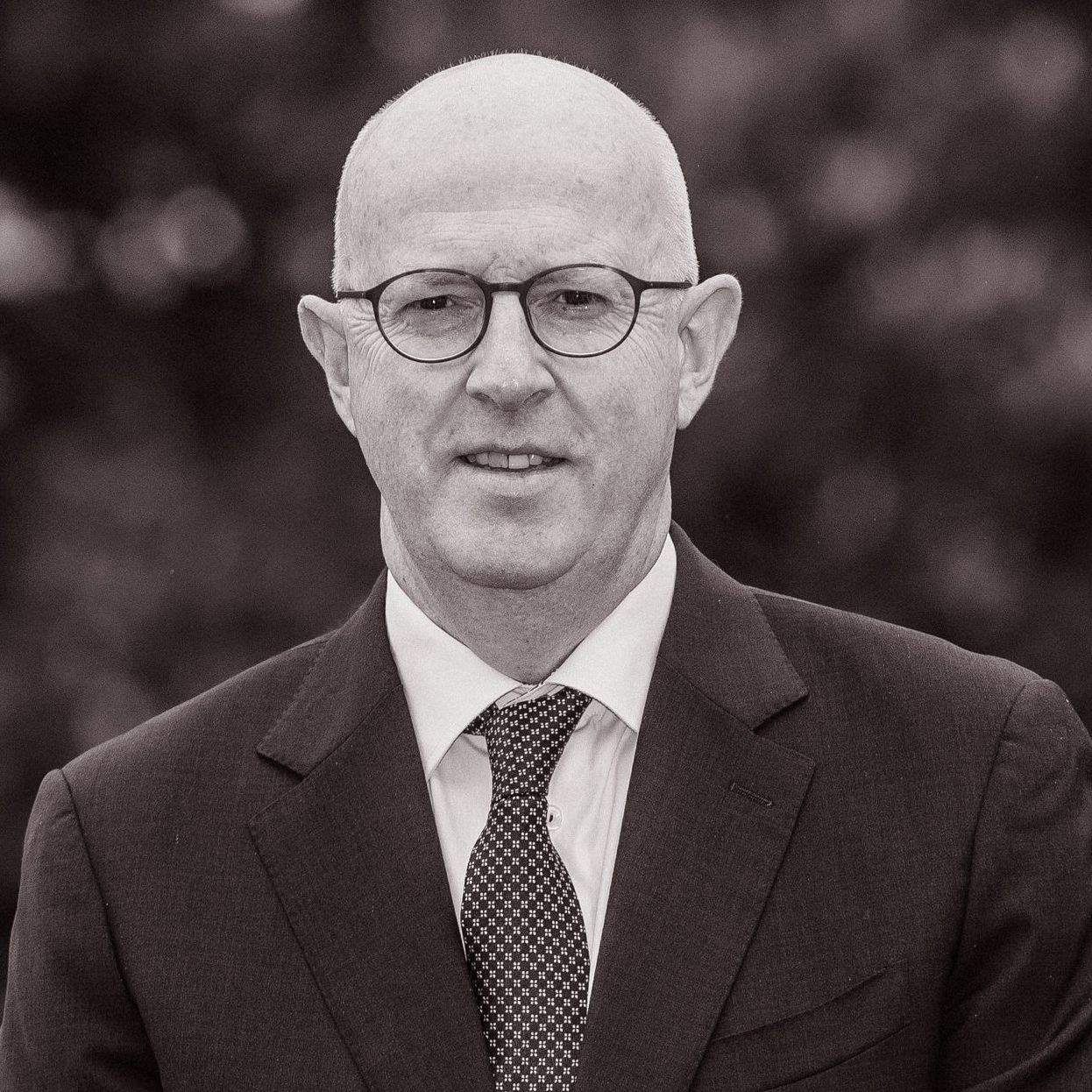 A bald man wearing glasses and a suit and tie