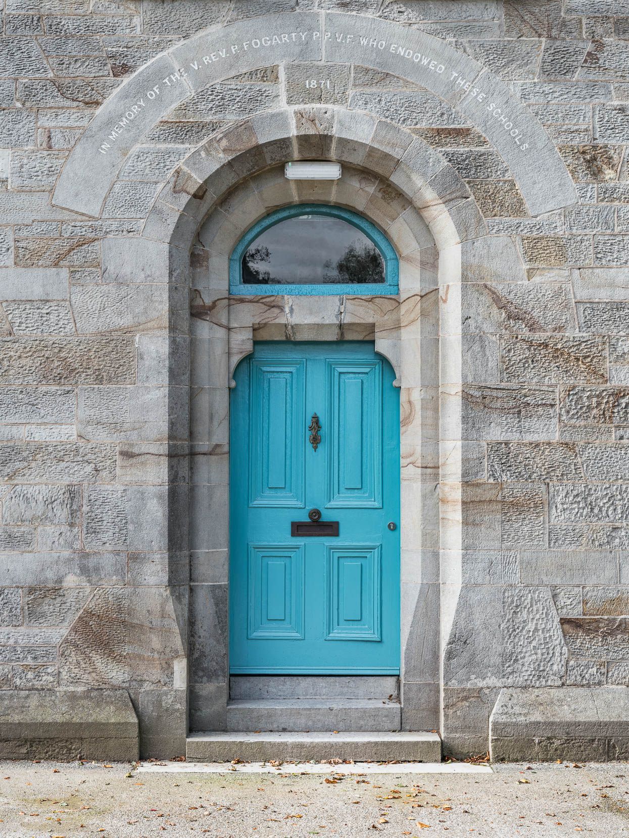 A blue door is on the side of a stone building.