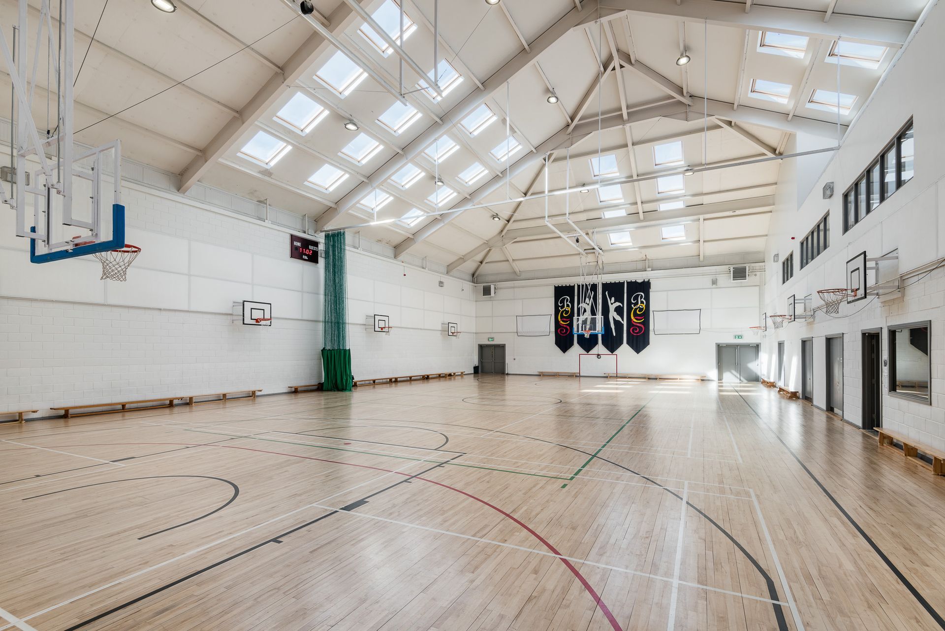 A large indoor basketball court with a wooden floor and a basketball hoop.