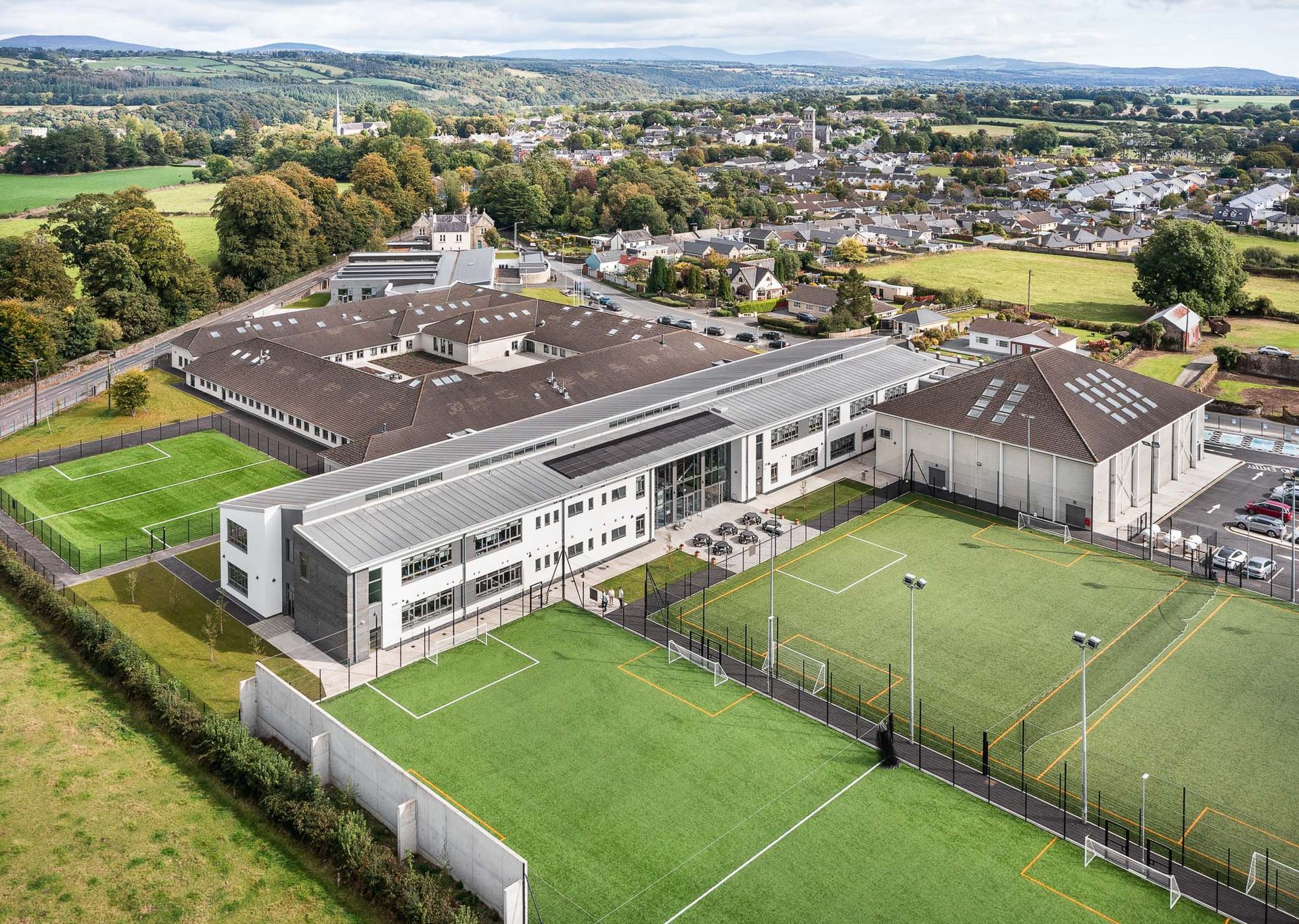 An aerial view of a large building with a soccer field in front of it.
