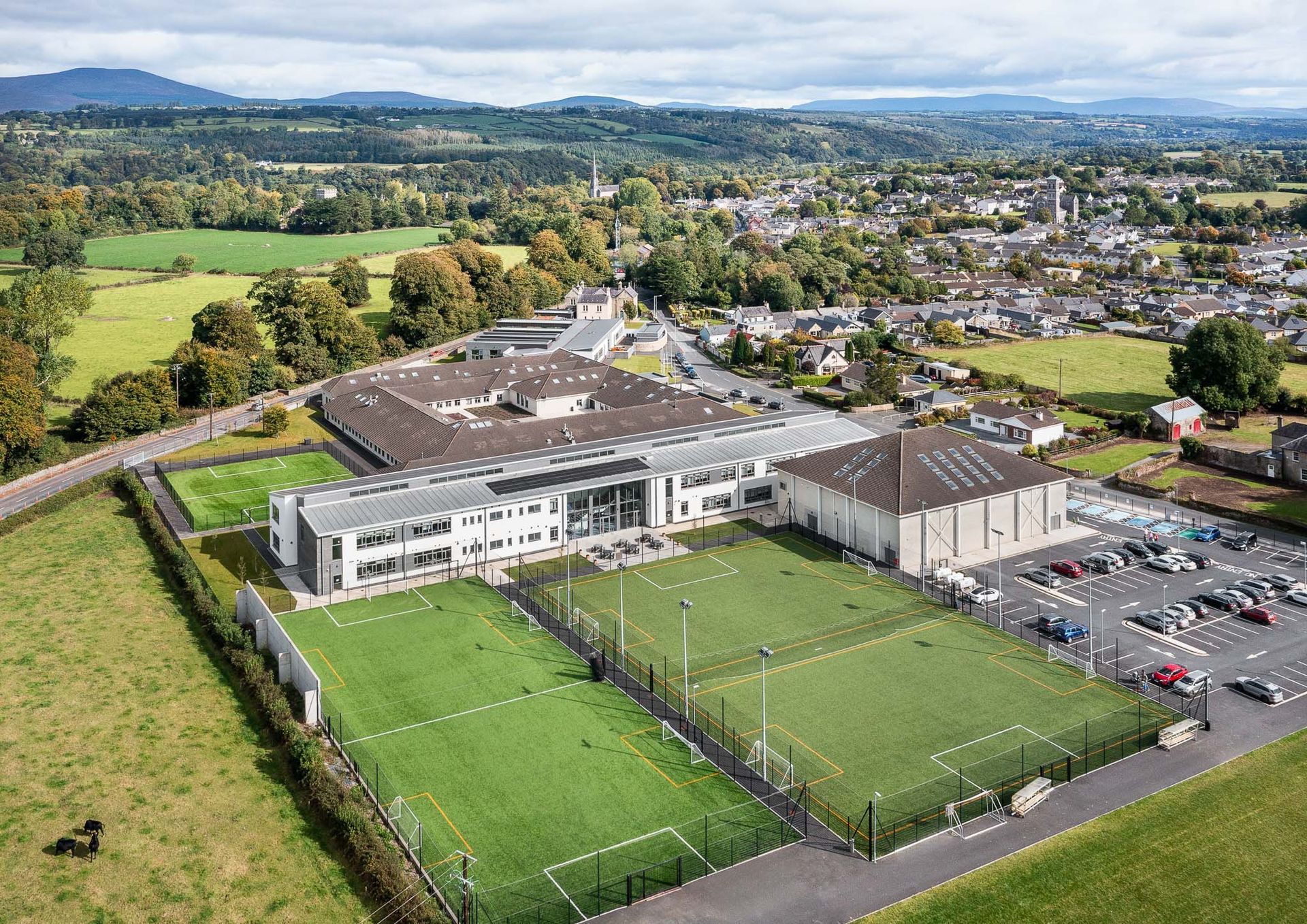An aerial view of a large building with soccer fields in front of it.