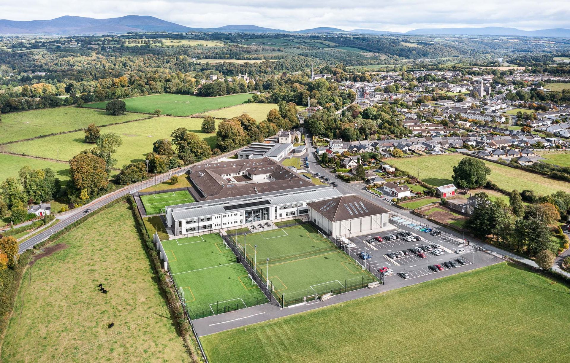 An aerial view of a school surrounded by fields and trees.