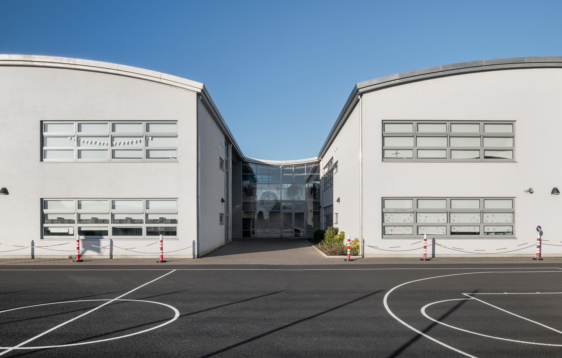 A large white building with a basketball court in front of it