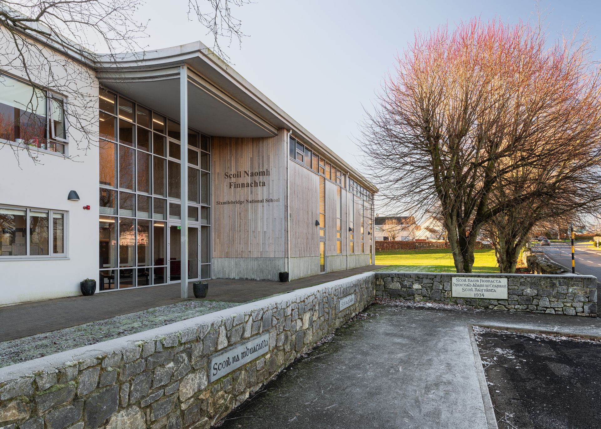 A large building with a stone wall and a tree in front of it.