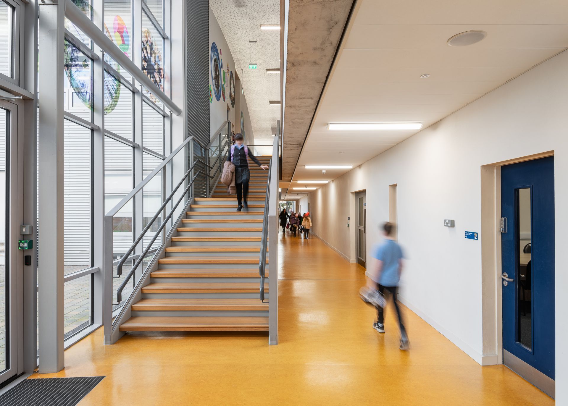 A person is walking down a set of stairs in a hallway.