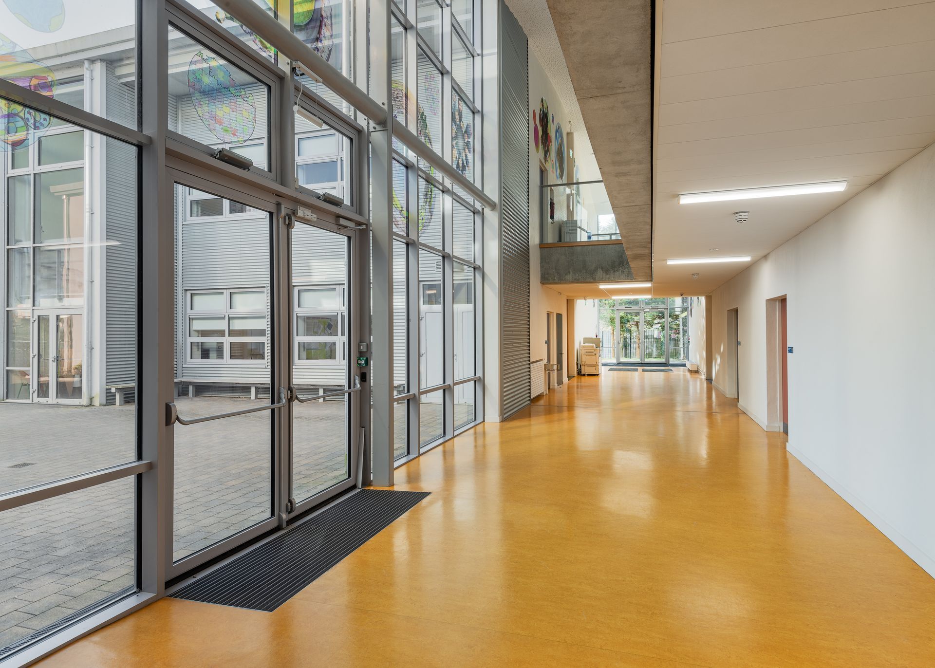 A long hallway in a building with lots of windows and doors.