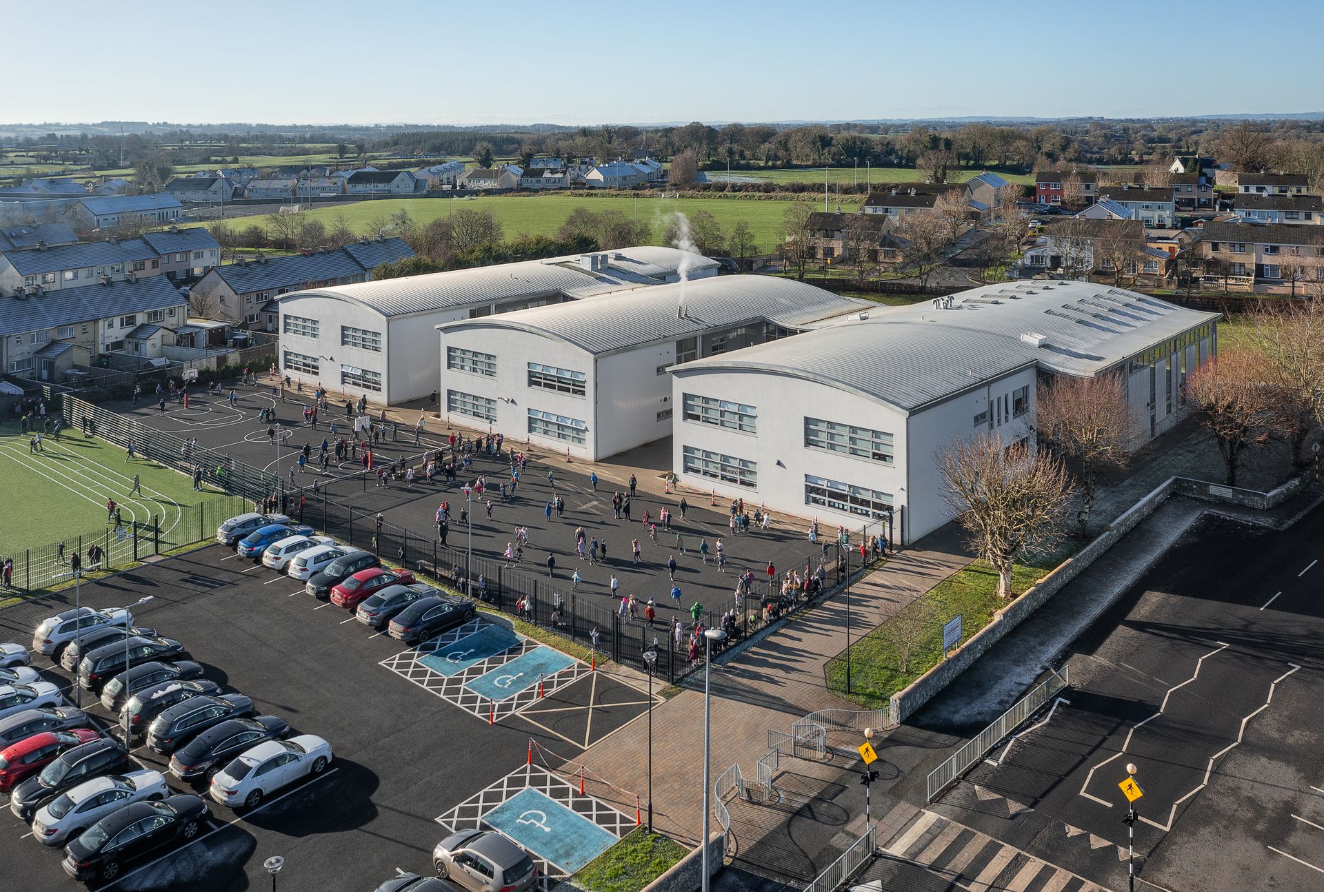 An aerial view of a school with a lot of cars parked in front of it.