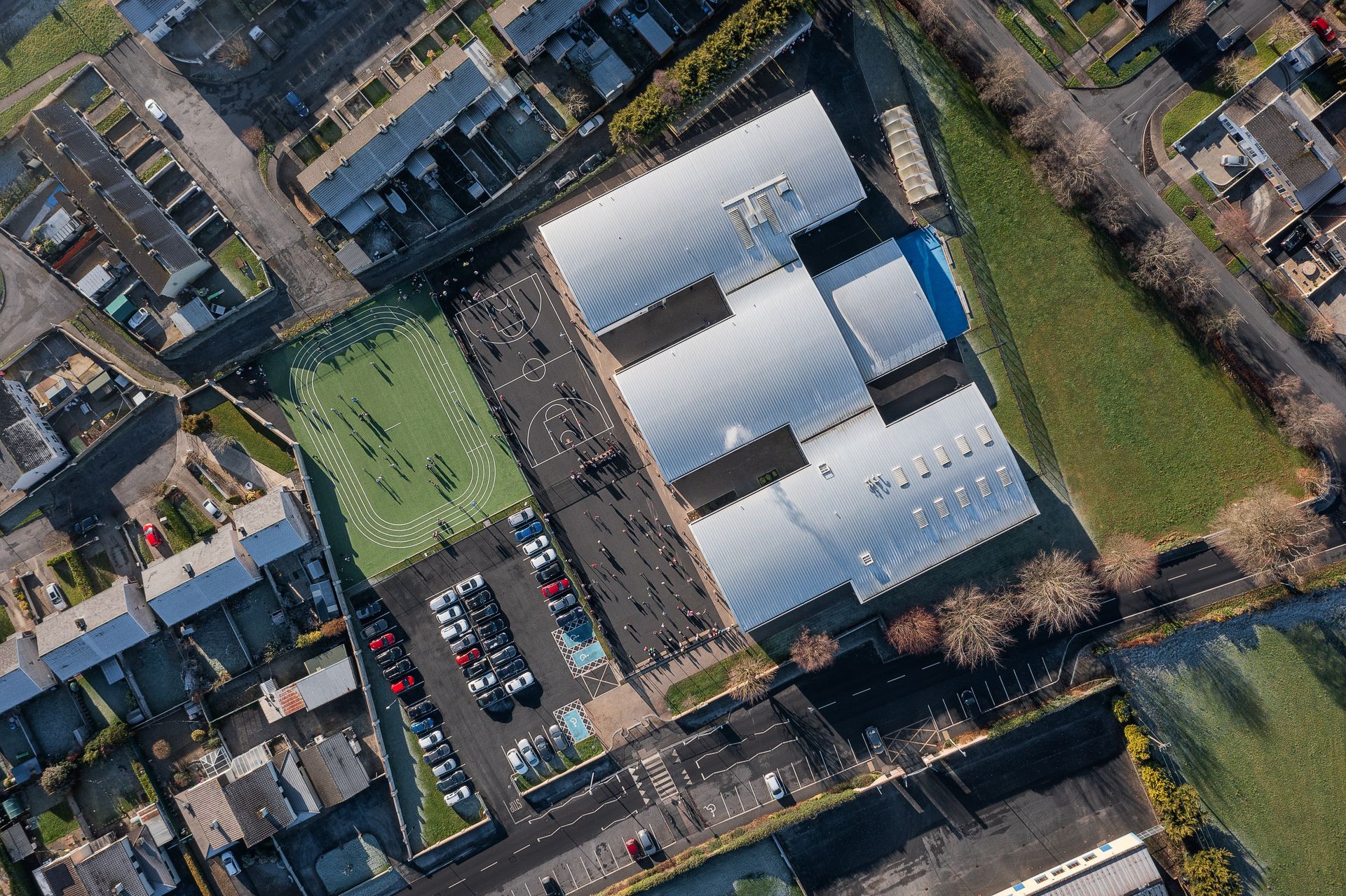 An aerial view of a school with a lot of cars parked in front of it.