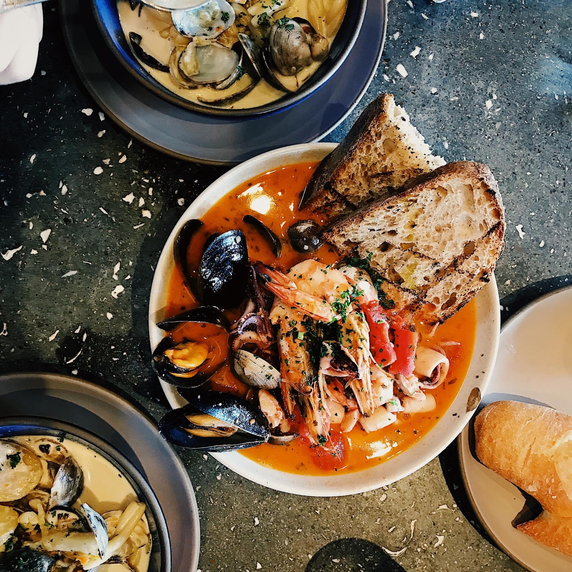 A table topped with bowls of seafood and bread