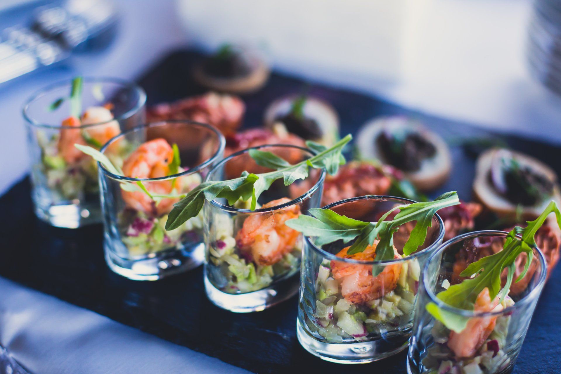 A tray of food in shot glasses on a table.