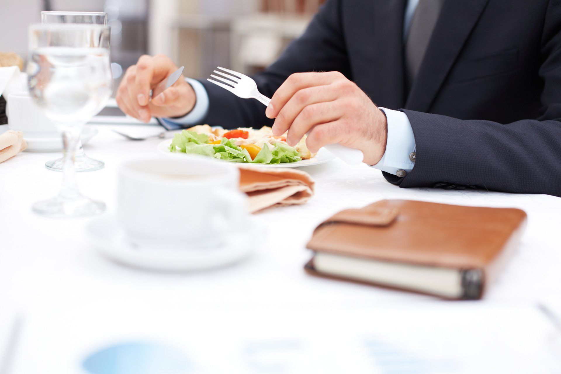 A man in a suit is sitting at a table eating a salad