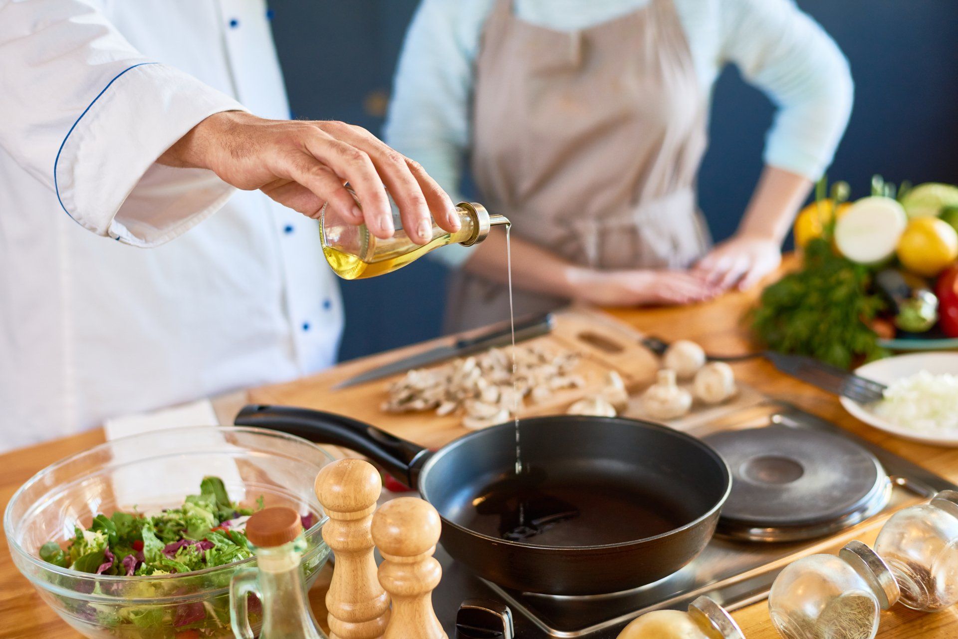 A man is pouring oil into a frying pan.