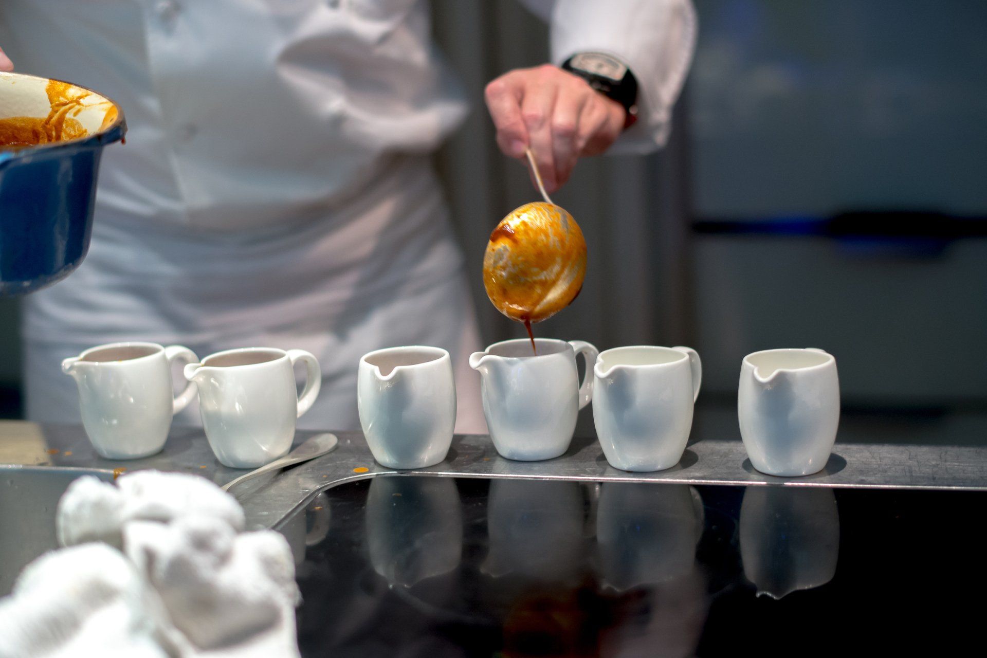 A person is pouring liquid into small cups on a table.