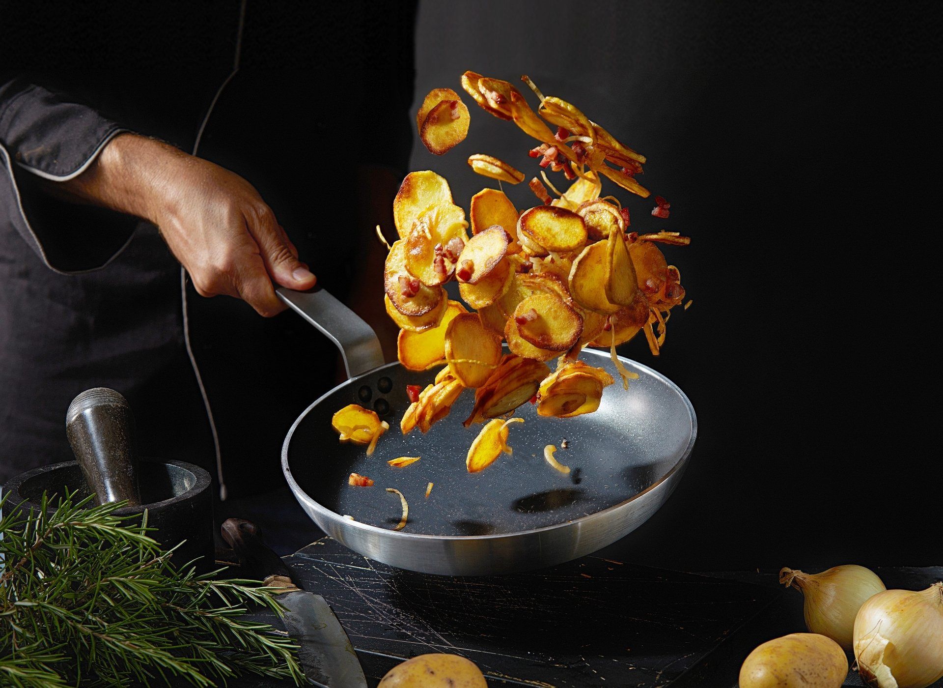 A person is cooking potato chips in a frying pan.