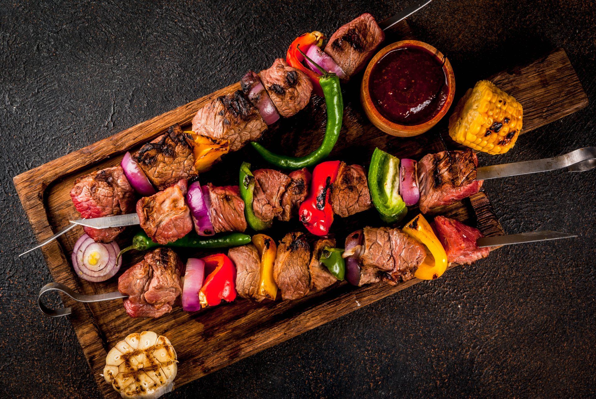 A wooden cutting board topped with skewers of meat and vegetables.