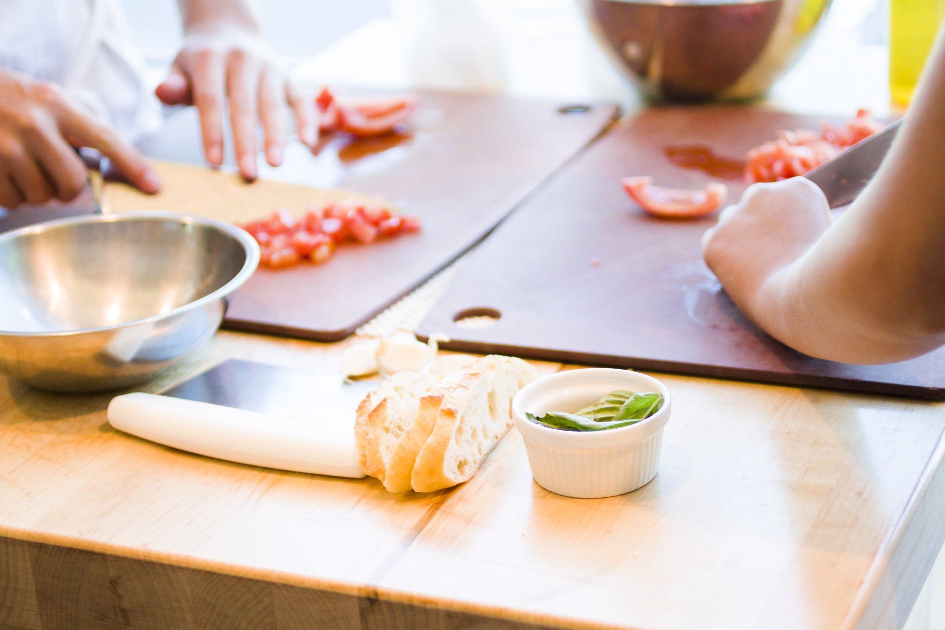 A person is cutting tomatoes on a wooden cutting board.