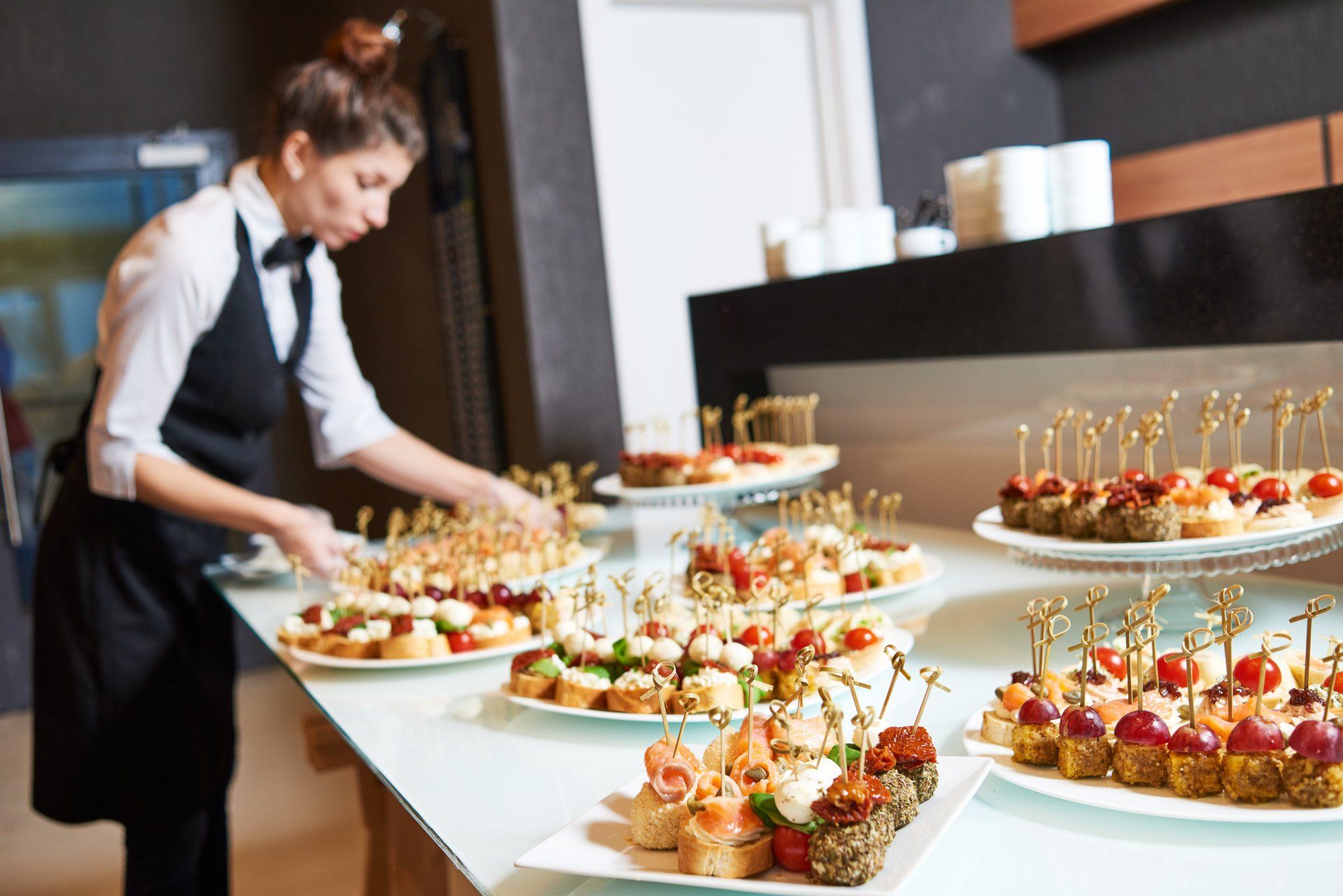 A woman is preparing food on a buffet table.