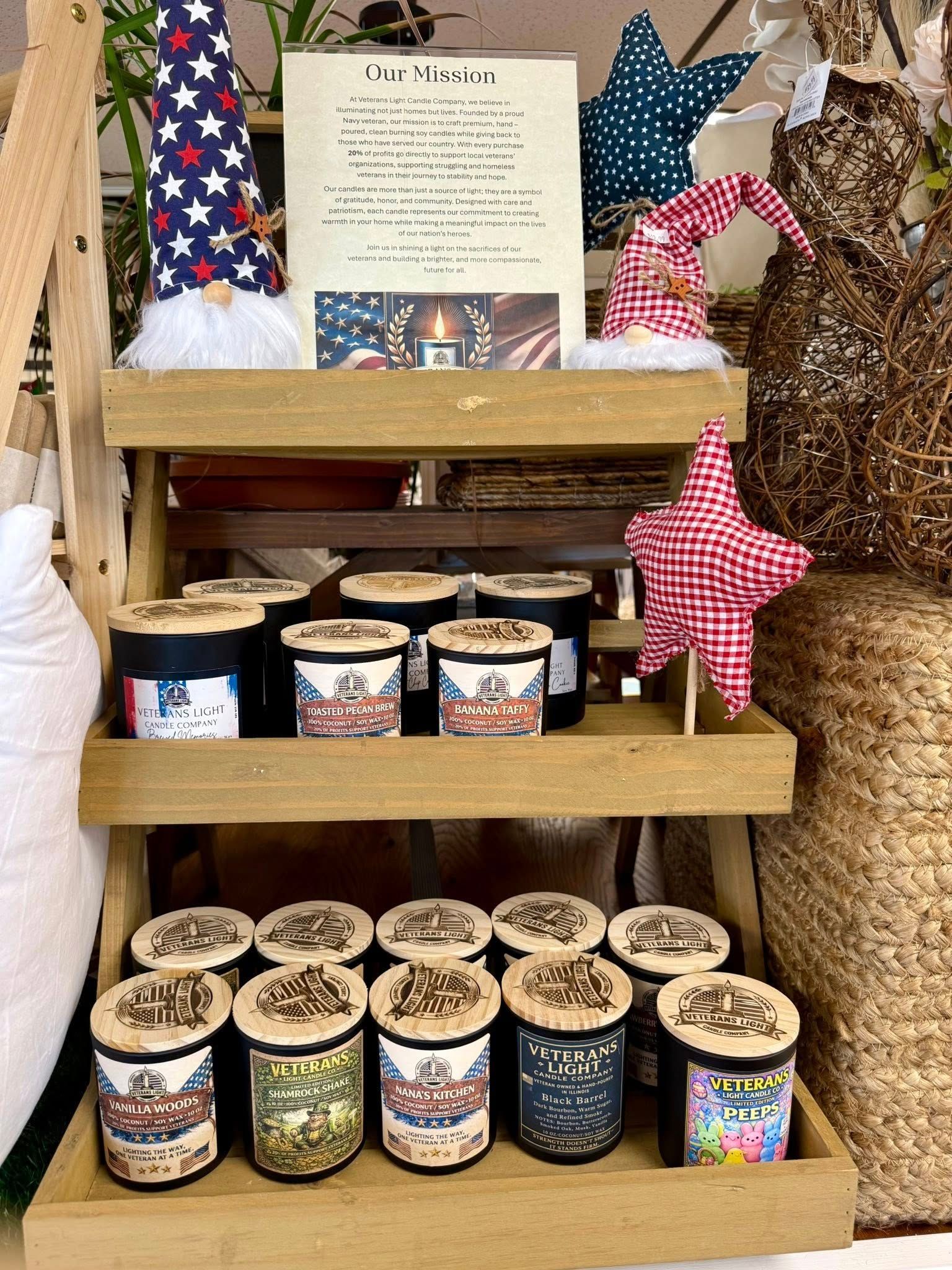 A tiered wooden shelf displaying patriotic-themed candles, plush gnomes, and fabric stars.