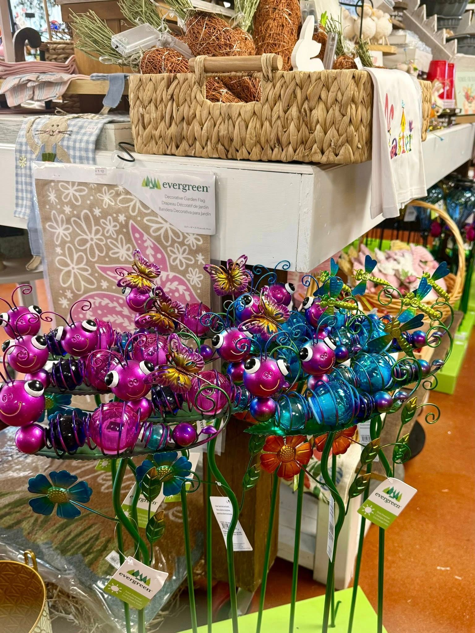 Vibrant metal flower garden stakes with pink and blue bulbs displayed in a retail store setting.