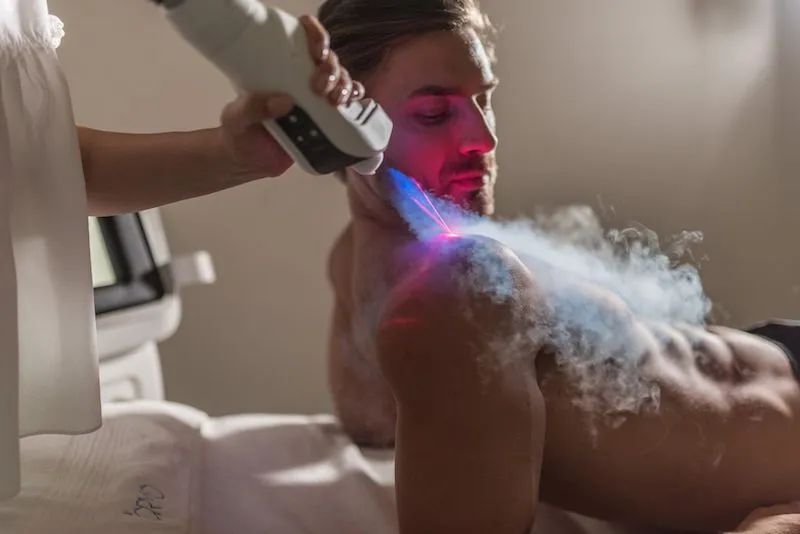 A man is getting a cryotherapy treatment on his shoulder.