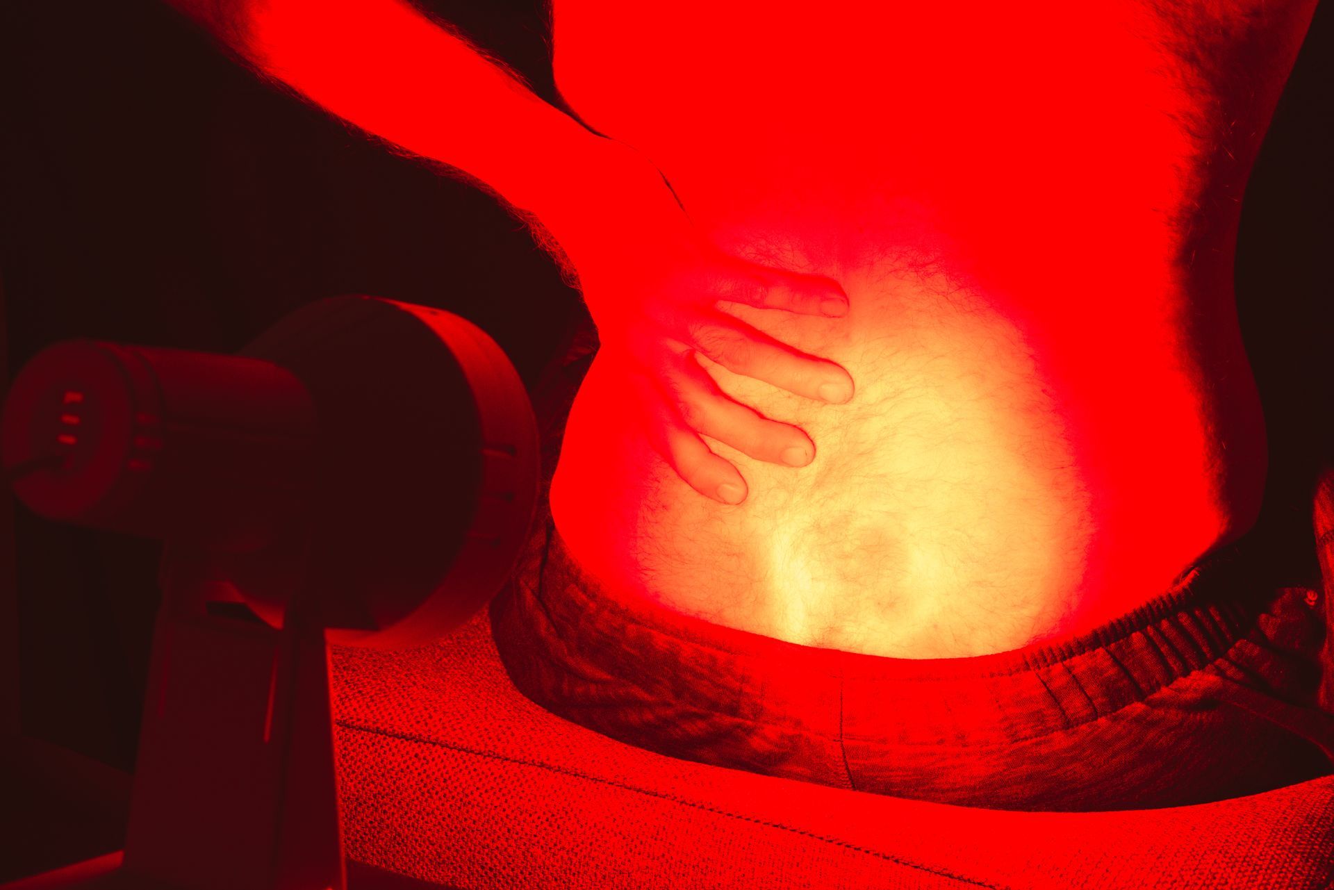 A person is sitting on a chair with a red light on their back.