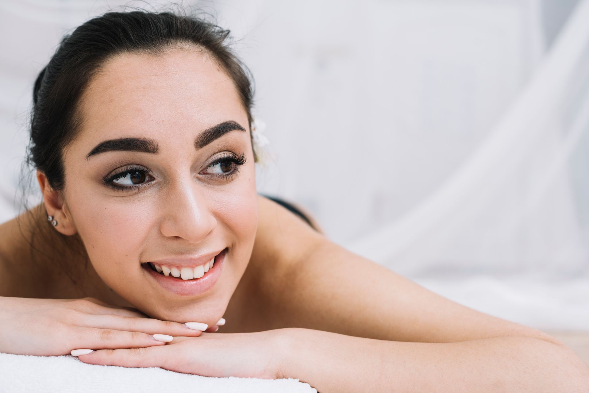 A woman is laying on her stomach on a towel and smiling.