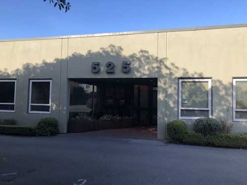 A single-story, light-tan commercial building with the number 525 mounted above a recessed entrance.