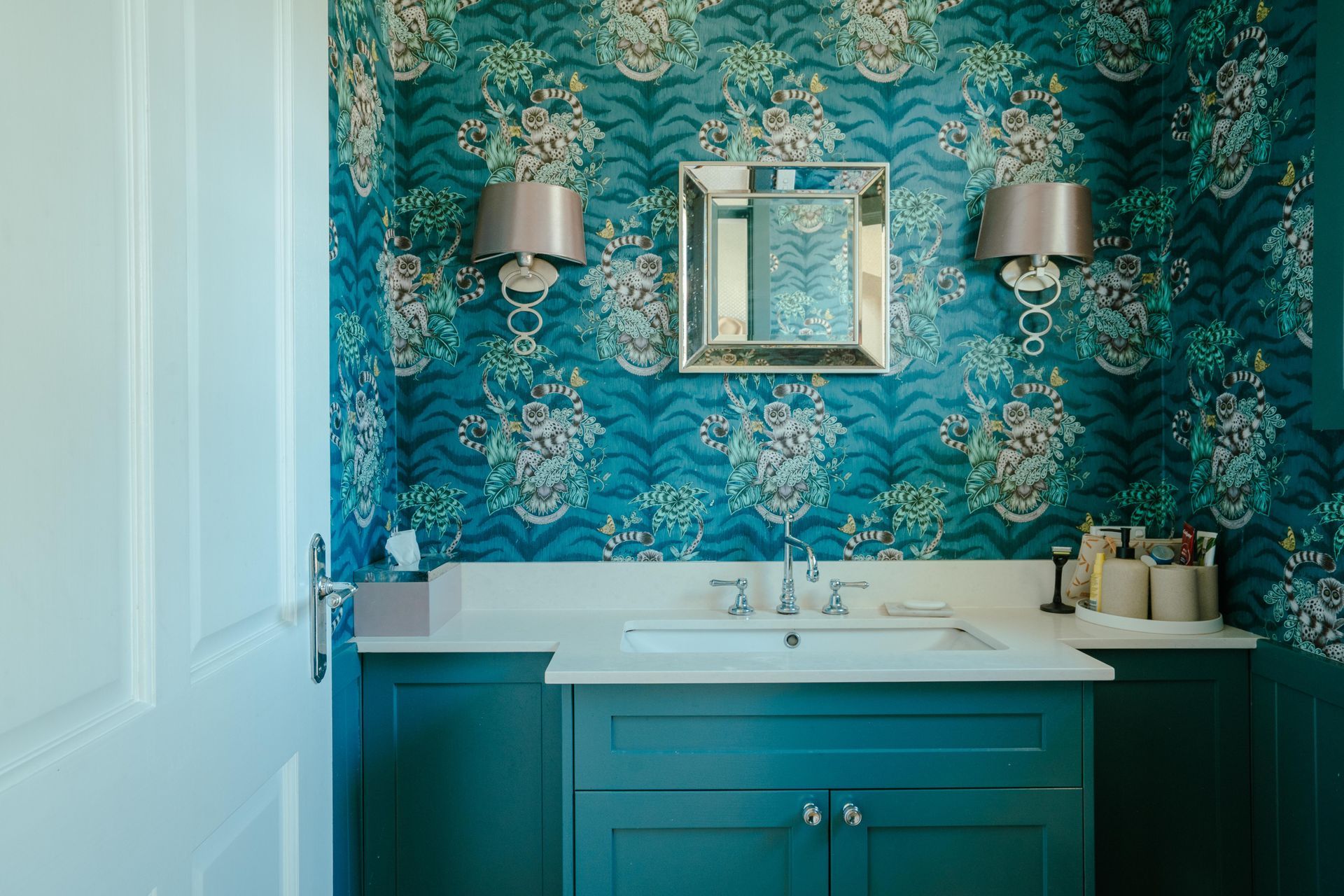 Teal bathroom with floral wallpaper, teal cabinet, white sink, silver sconces, and mirror. — Mittagong Painting in Welby, NSW