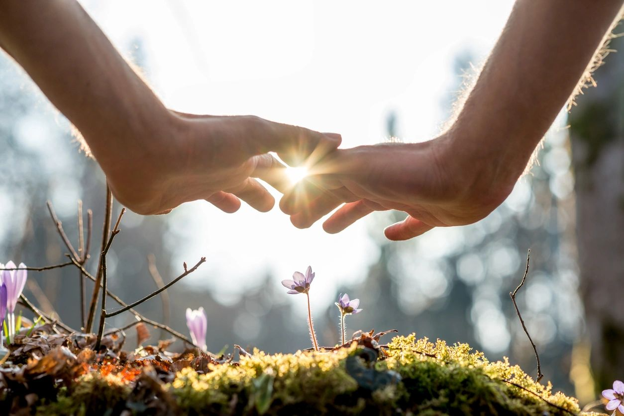 A person is touching the sun with their hands.