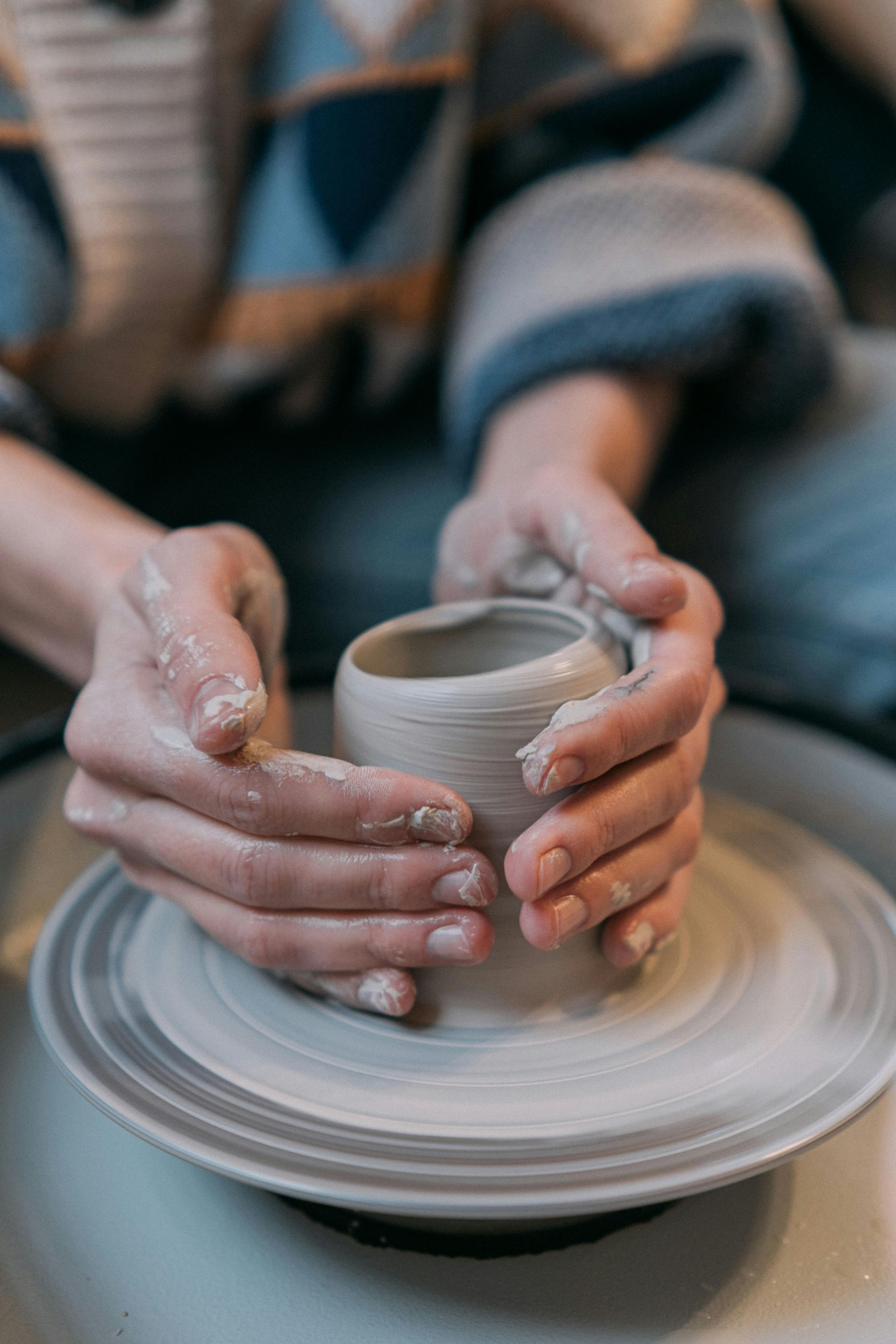 A person is making a pot on a pottery wheel.