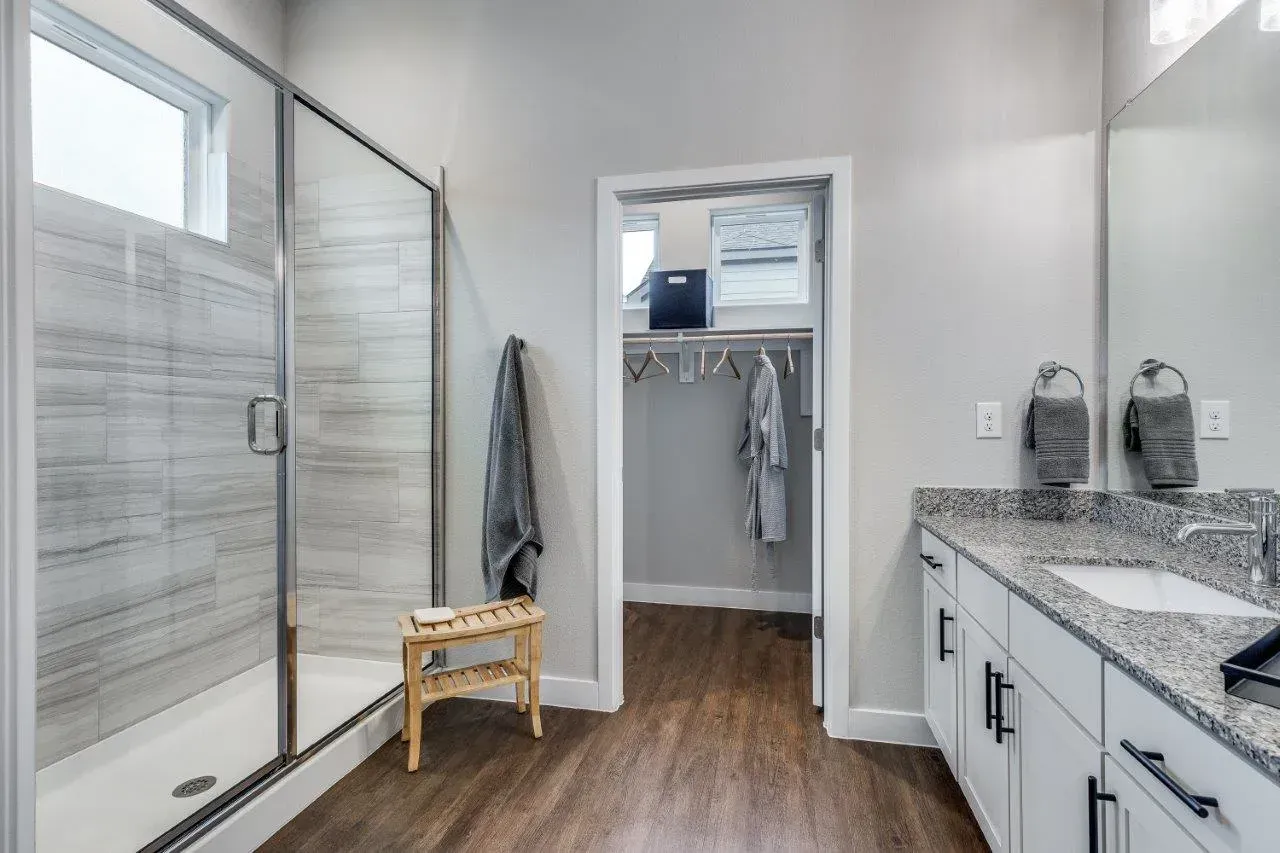 A bathroom with a walk-in shower, sink, and mirror.
