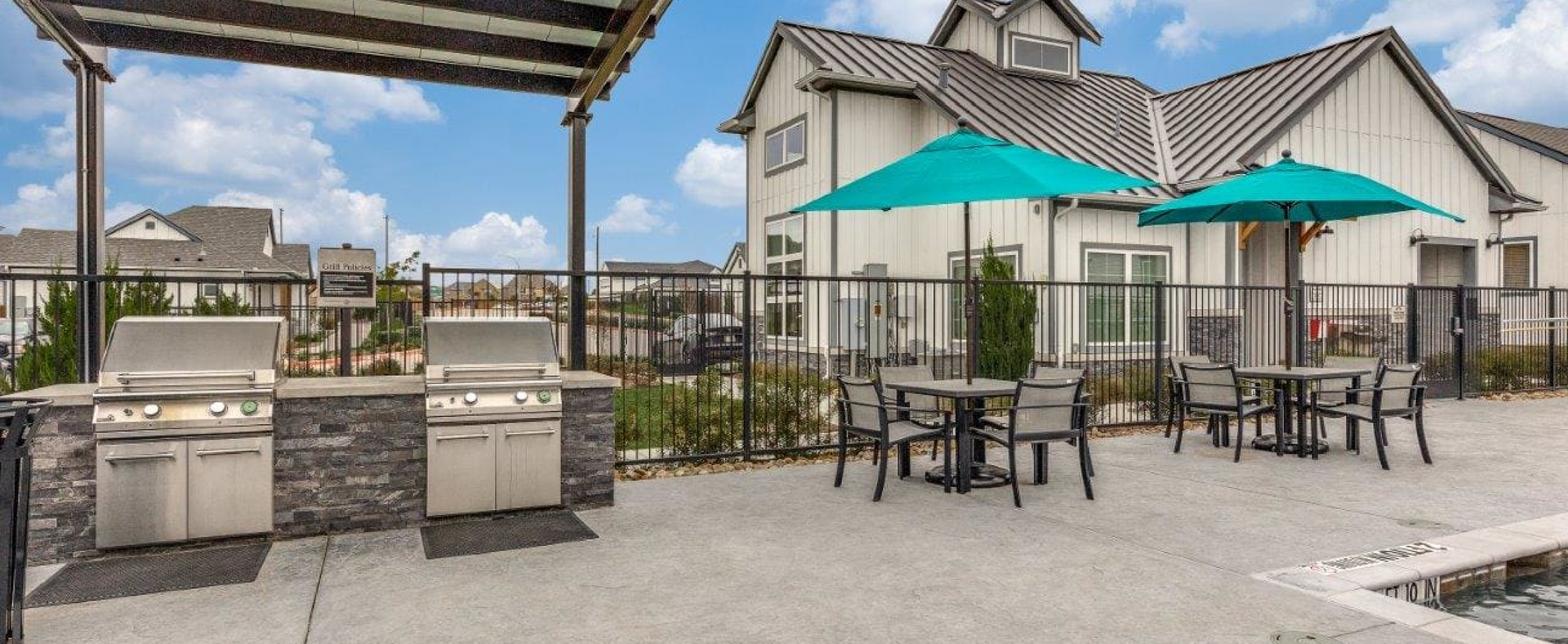 A patio with tables and chairs and an umbrella.