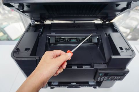 tecnico con cacciavite per riparare fotocopiatrice