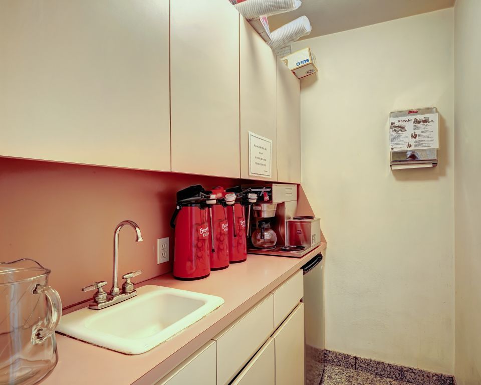 A kitchen with a sink , coffee maker , and pitcher.