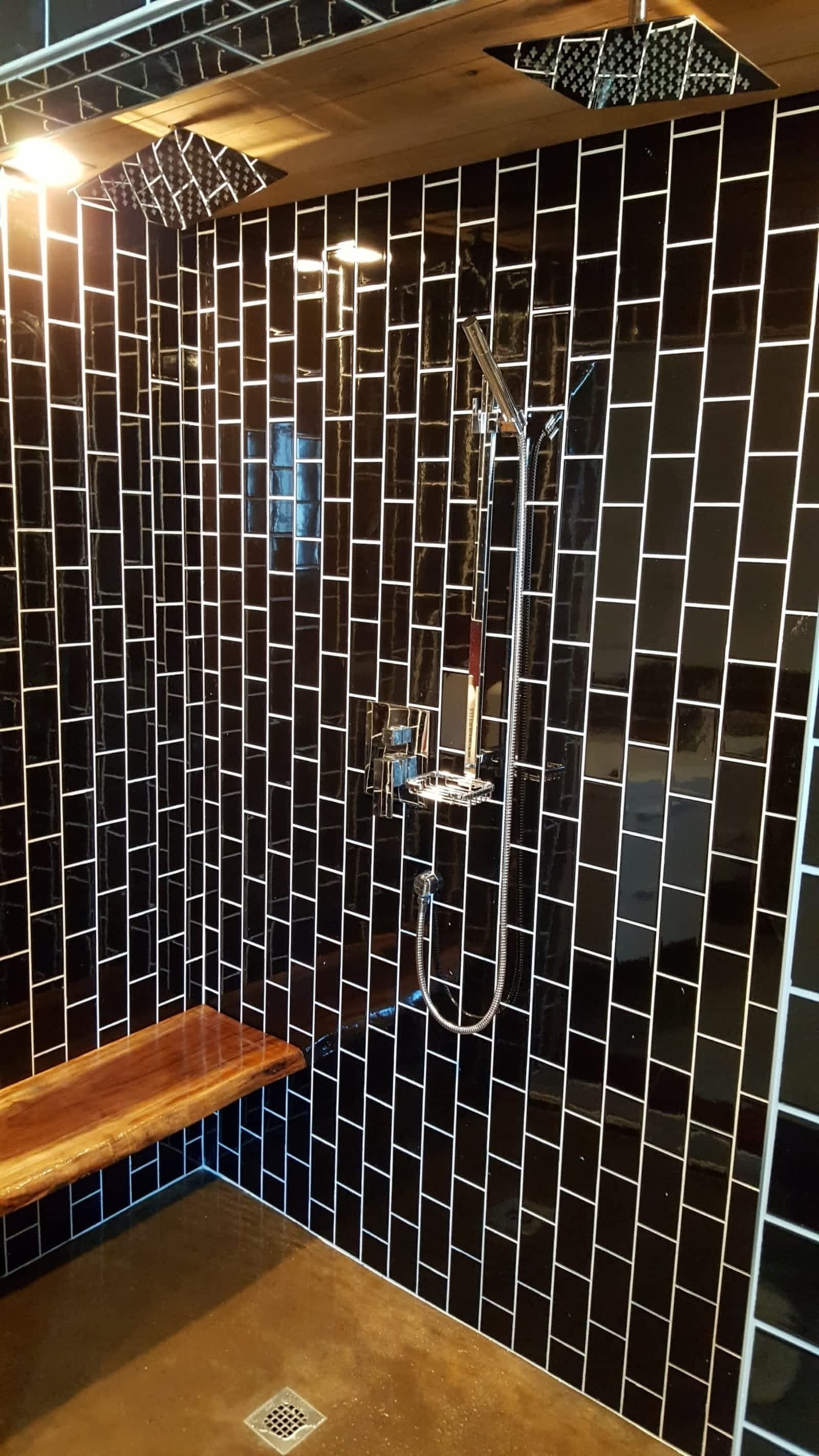 A bathroom with black tiles and a wooden bench.