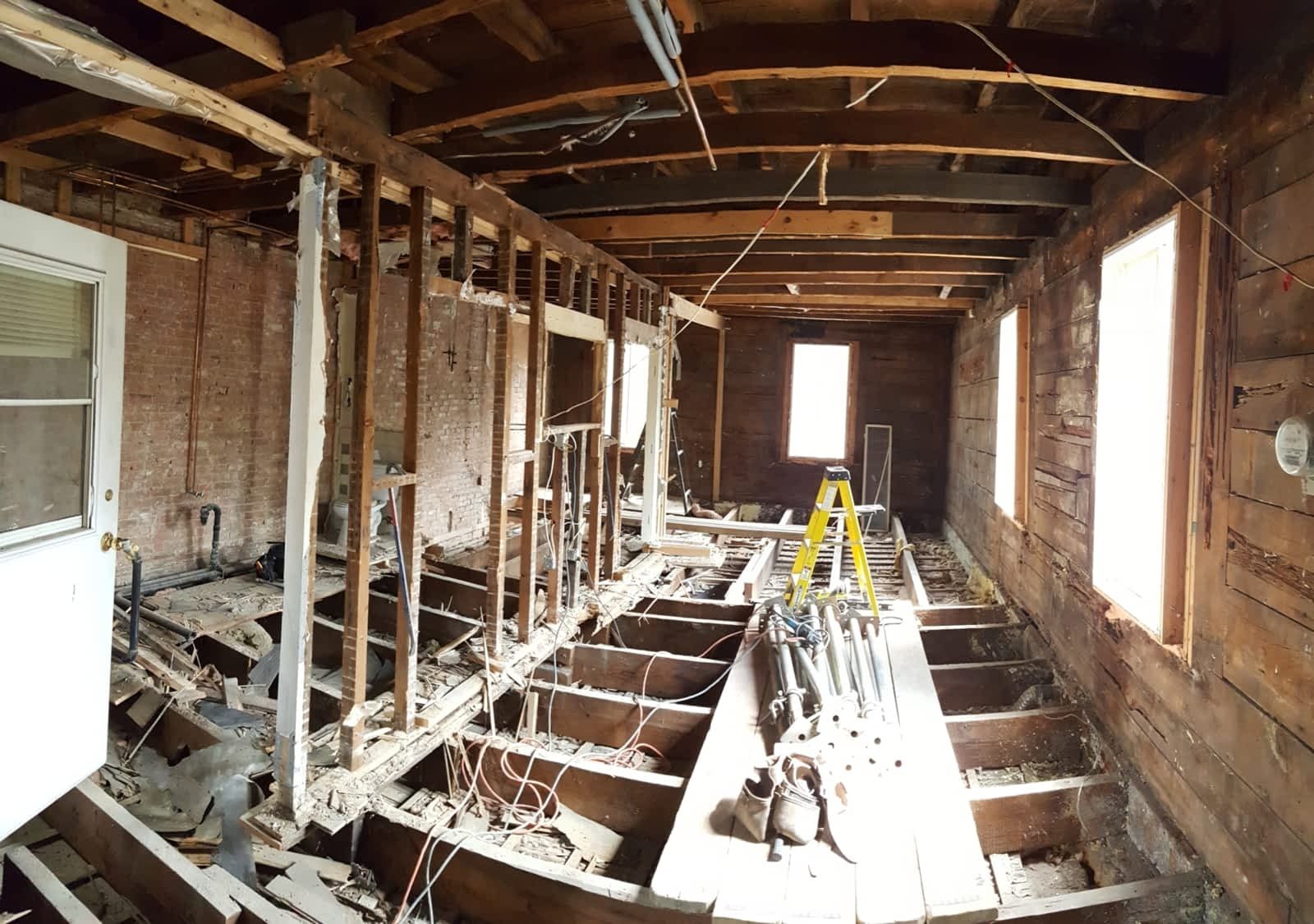 The inside of a building under construction with a yellow ladder on the floor.