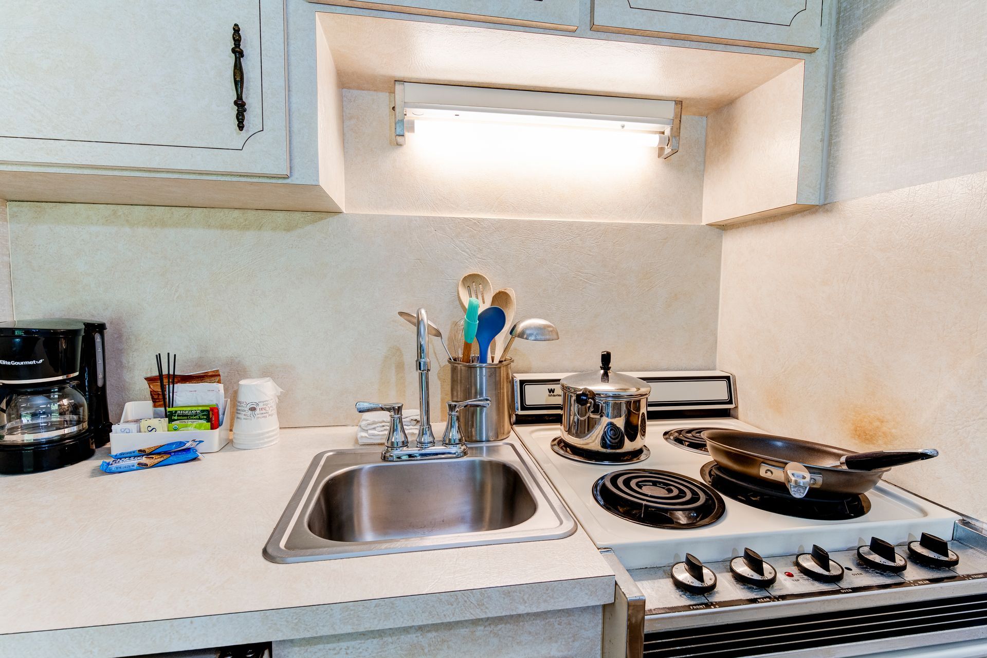 A kitchen with a sink stove and pots and pans