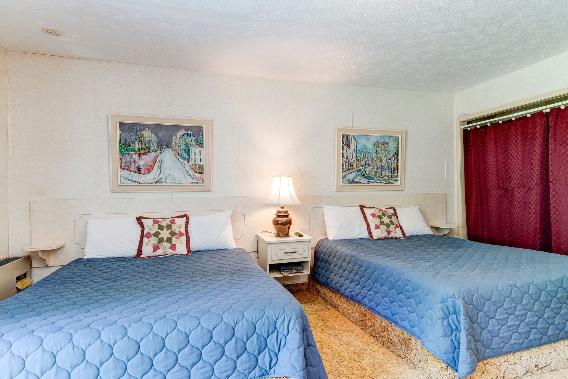 A hotel room with two beds and a lamp.