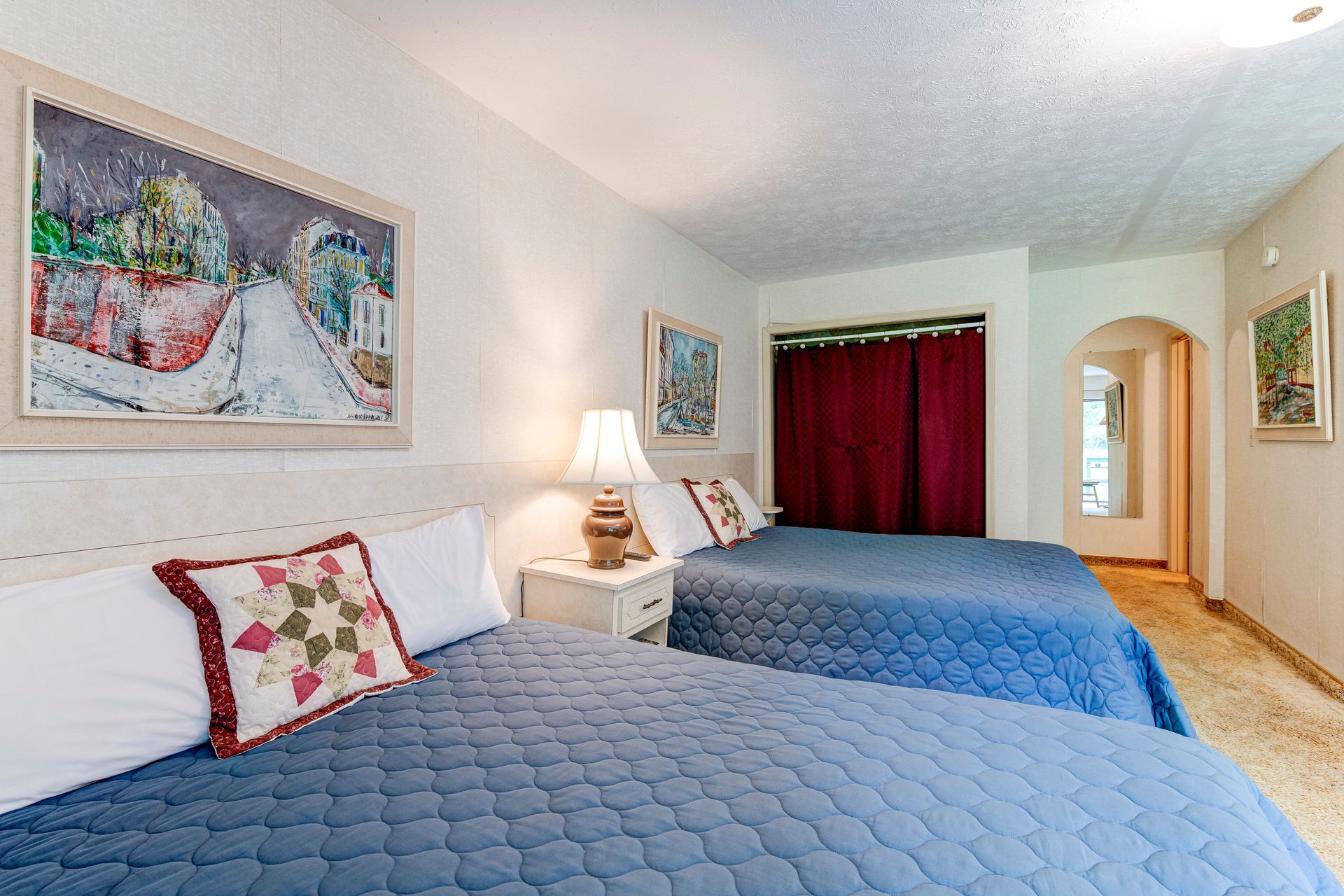 A hotel room with two beds and two paintings on the wall.