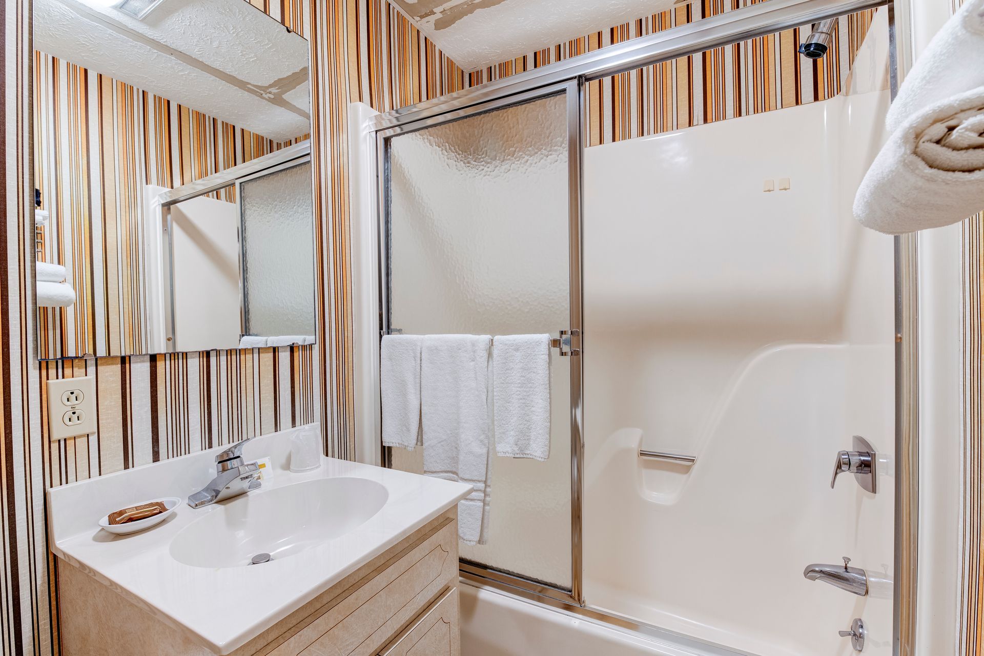 A bathroom with a sink , tub , shower and mirror.