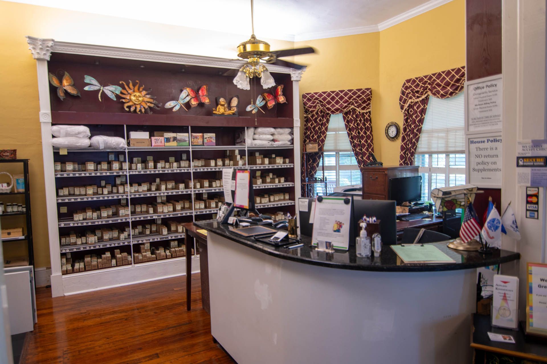 A counter in a store with a lot of shelves and a ceiling fan