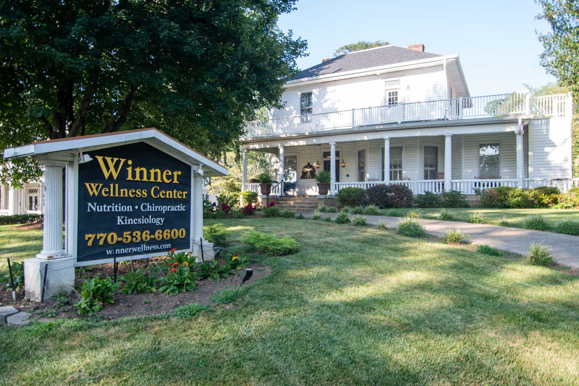 A large white house with a winner wellness center sign in front of it