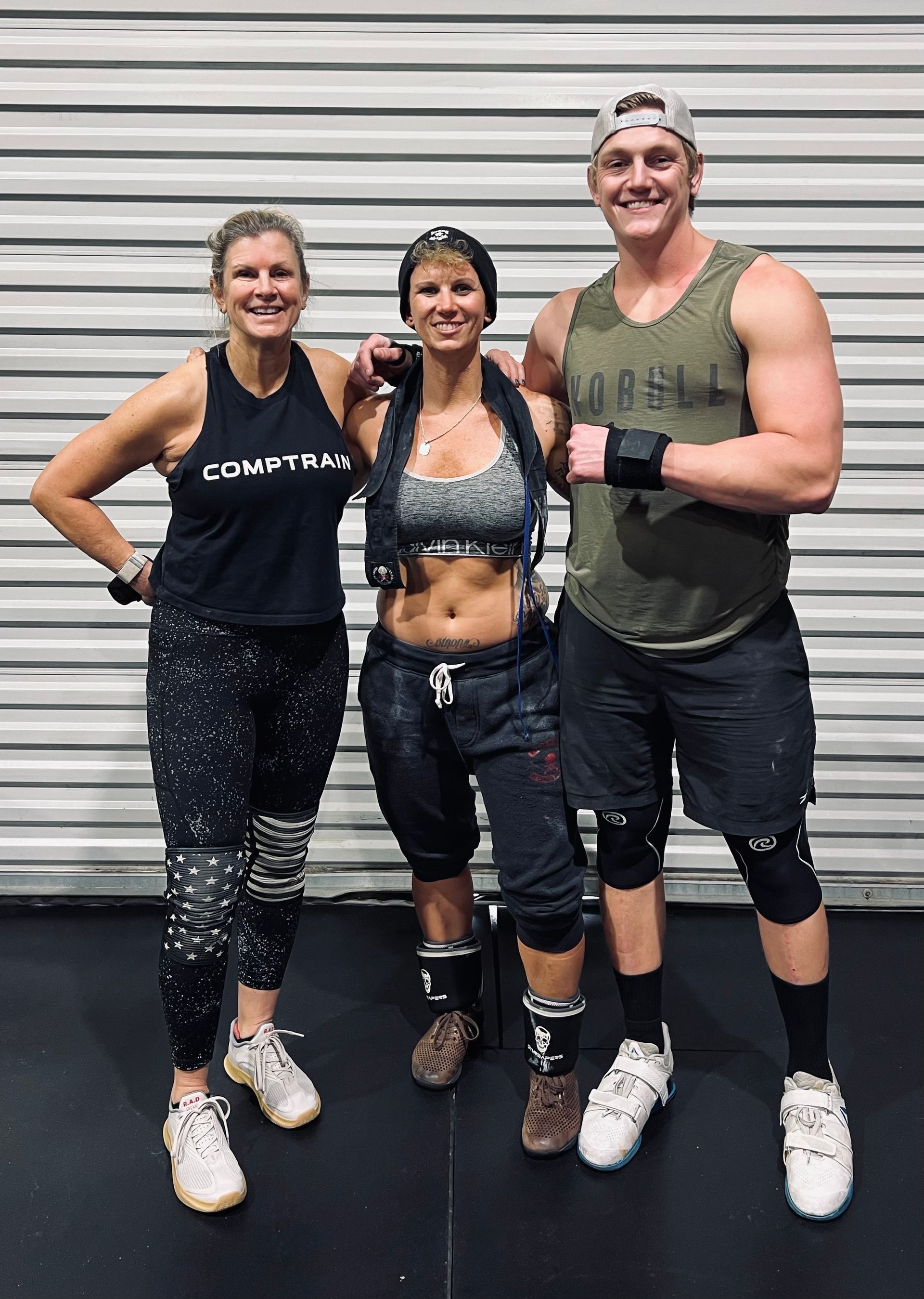 A man and two women are posing for a picture in a gym.