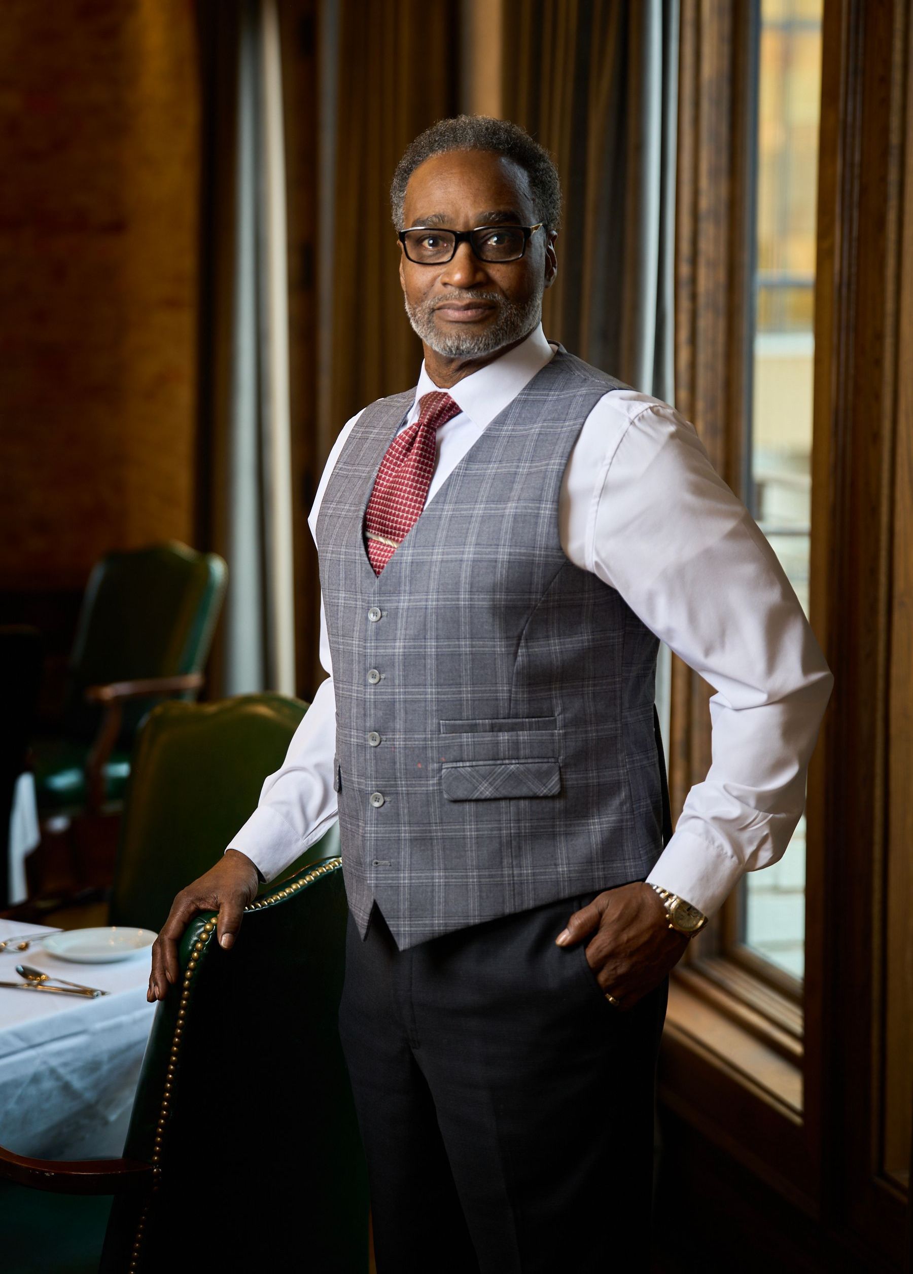 A man in a suit and tie is standing in front of a window.