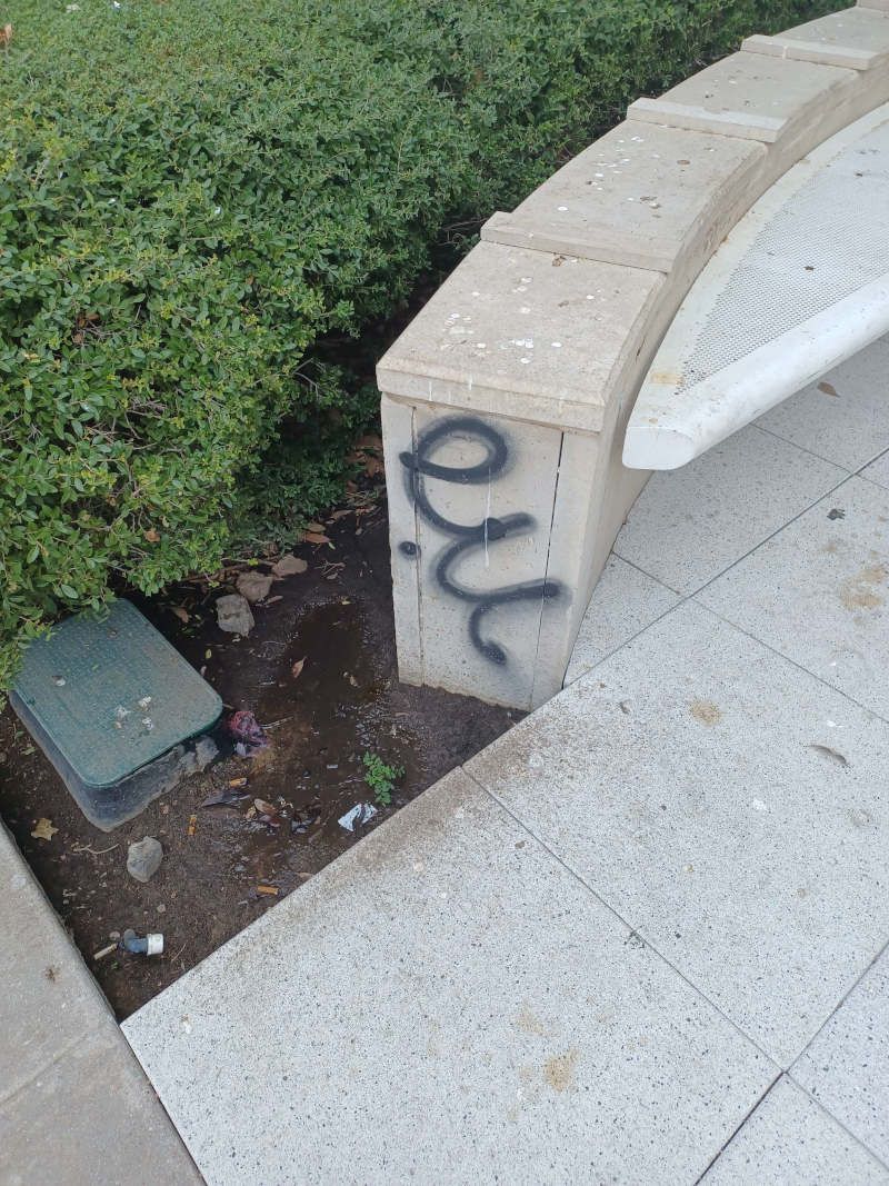 A white bench with graffiti on the side of it.