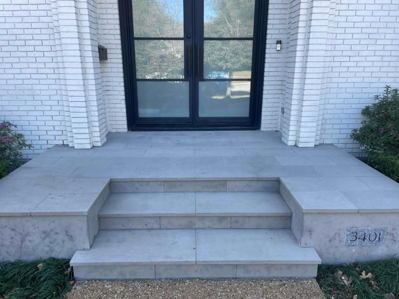 A white brick house with a black door and steps