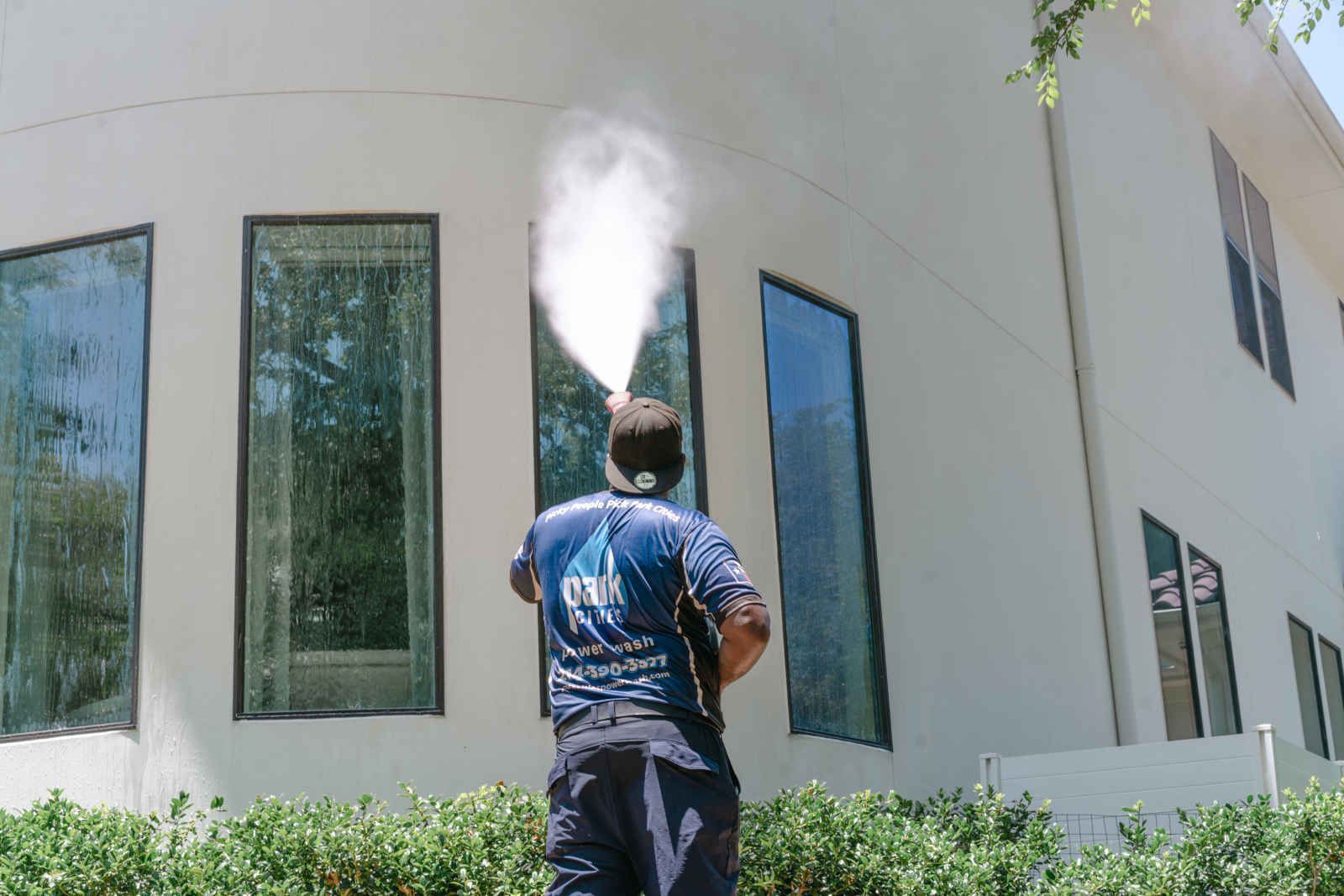 A man is spraying water on the side of a building.