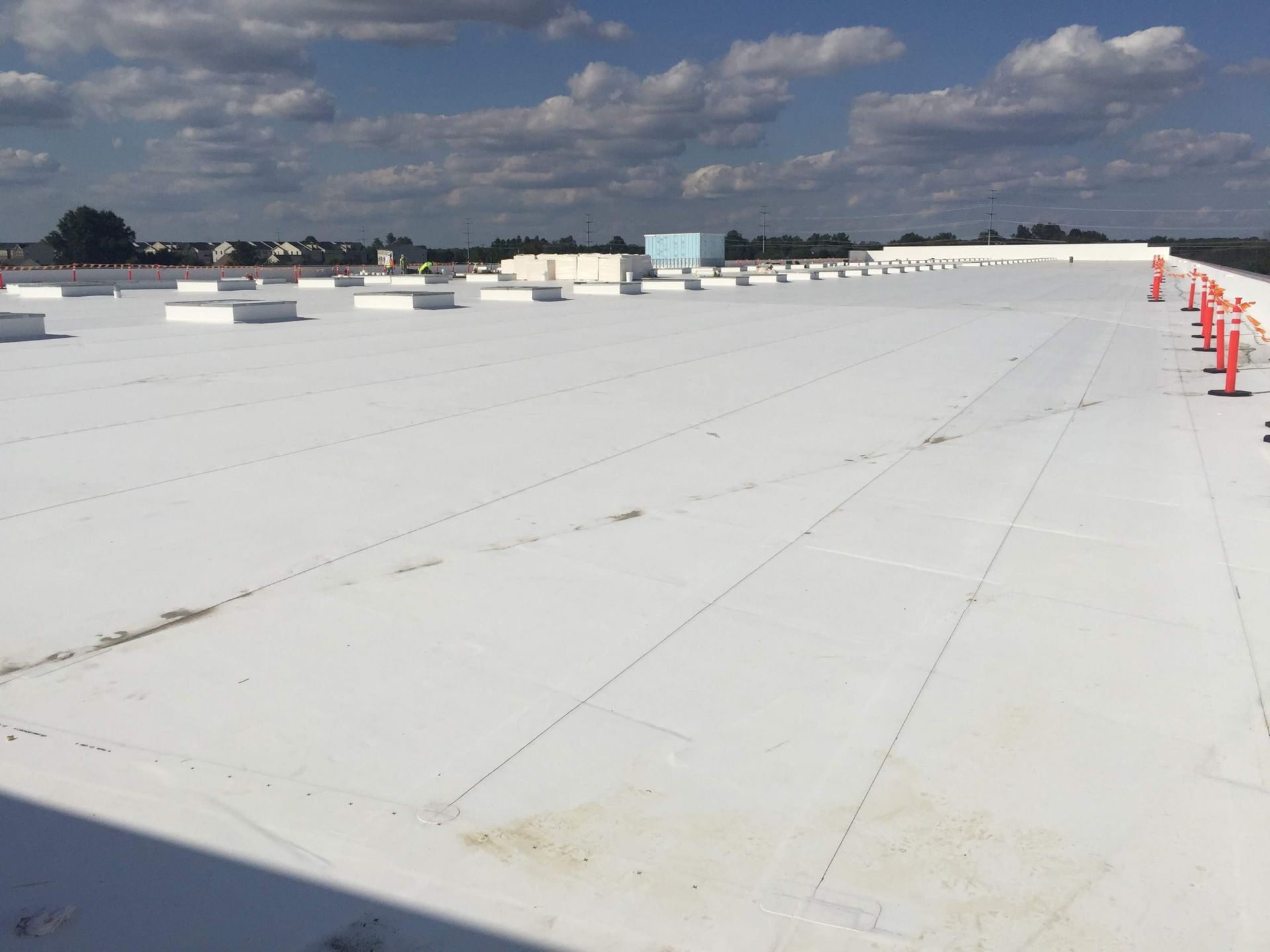 A large white roof with orange cones on it on a sunny day.