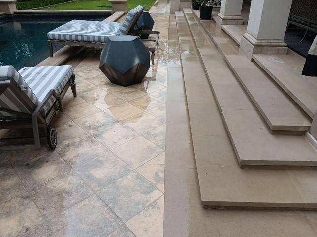 A patio with chairs and stairs next to a pool.